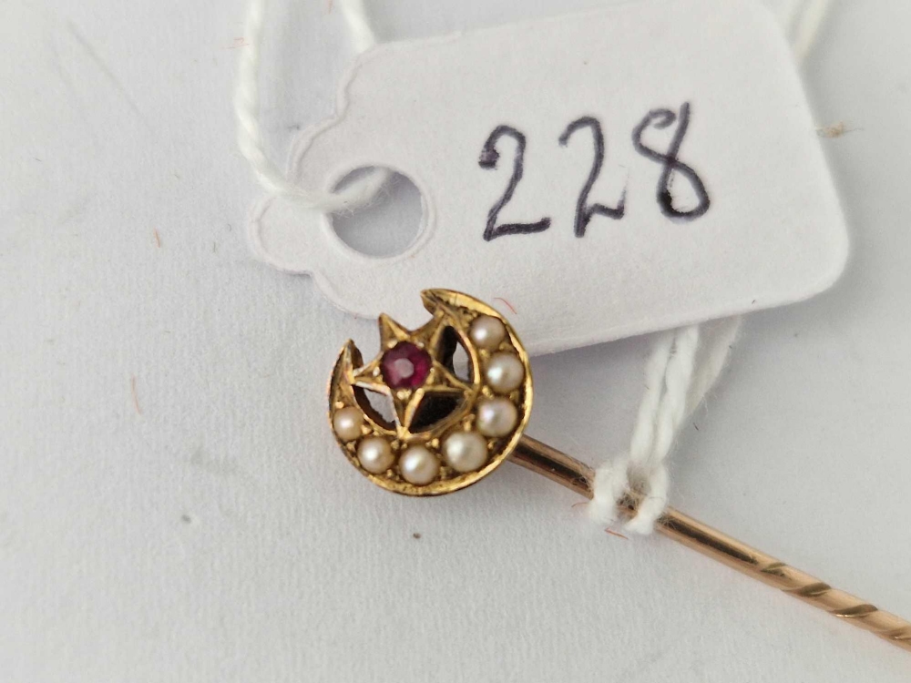 A gold crescent stick pin with pearl and ruby top