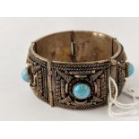 A hand made five panel decorated bangle each ornate panel with central turquoise matrix bead