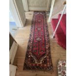 An oriental red ground runner with pole medallion, 10ft 6" x 2ft 6"