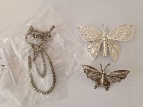 Two silver filagree butterfly brooches one with articulated wings and a silver marcasite cat brooch
