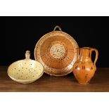 A 19th Century Glazed Terracotta Jug, and two drainers. The jug decorated with brown drip glaze