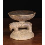 A Small African Tribal Stool carved from heart-wood with a slightly dished round top raised on the