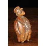 A 19th Century Carved Coquilla Nut Snuff Box in the form of a big-nosed man with glass bead inset