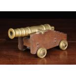 A 19th Century Brass Table Cannon mounted on a wooden carriage on brass wheels,