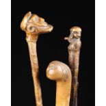 Three Antique Wooden Walking Sticks with decoratively carved handles.