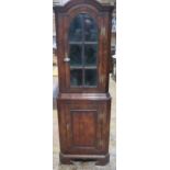 A walnut one piece corner cupboard with an astragel glazed door over a cupboard door and painted