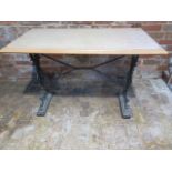 A cast iron base table with a wooden top - Height 73cm x 106cm x 60cm