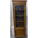 A 1930's tall oak bookcase with a single leaded glazed door over a panel door, one pane broken