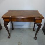 A restored George II mahogany fold over card table with a shaped top on carved cabriole legs and