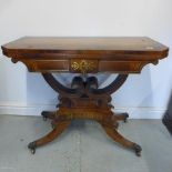 A Regency brass inlaid rosewood fold over card table on a twin scroll support and splayed quatrefoil