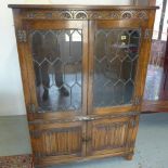 An oak display cabinet/bookcase the top with leaded glazed doors and two linen fold lower doors -