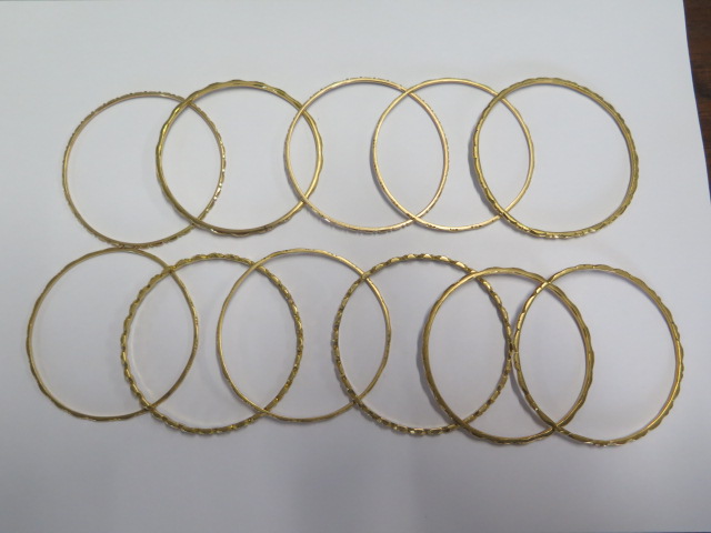 Eleven yellow metal bangles - surface test to approx 18ct gold - 6.2cm external diameter - total