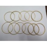 Eleven yellow metal bangles - surface test to approx 18ct gold - 6.2cm external diameter - total