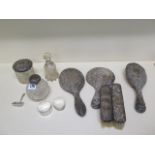 A collection of four silver back brushes, a mirror, two bottles and a tidy with silver tops, two