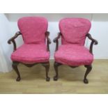 A pair of upholstered open armchairs with carved eagles head arms