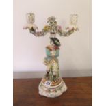 A floral encrusted porcelain twin branch figural candelabra of a skater - Height 35cm - some foliate