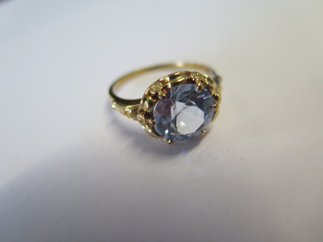 A yellow metal dress ring set with a round 10mm synthetic blue spinel claw set within a looped - Image 2 of 3