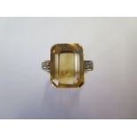 A yellow metal dress ring - a centre emerald cut citrine in four claw setting flanked by two