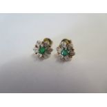 A pair of emerald and diamond set cluster earrings centring on a circular mixed cut medium colour
