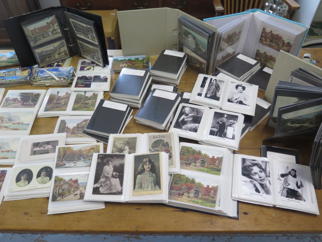 A large collection of Victorian and later postcards in over 70 small folders and albums including