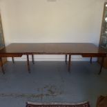 A Georgian mahogany pull out dining table with three leaves raised on eight turned legs with brass