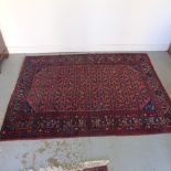 A hand knotted woollen rug with a red field - 206cm x 148cm - generally good condition