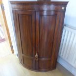 A Georgian mahogany bow fronted corner cupboard internally with three shelves and a drawer -