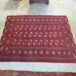 A hand knotted woollen rug with a red field - 192cm x 135cm - generally good condition - sold by