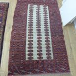 A small hand knotted woollen rug with a cream field - 176cm x 97cm - some wear to fringes