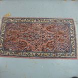 A small hand knotted woollen rug with a pink field - 130cm x 68cm - good condition
