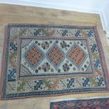 A small hand knotted woollen rug with a cream field - 141cm x 92cm - some wear mainly to fringes,