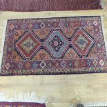 A small hand knotted woollen rug with a geometric multicoloured centre - 135cm x 80cm - bought