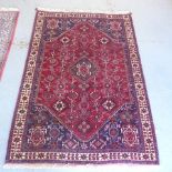 A hand knotted woollen rug with a red field - 182cm x 120cm - bought from Persian Tribal Rugs for £