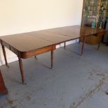 A Georgian mahogany pull out dining table with three leaves raised on eight turned legs with brass