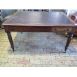 A 19th century mahogany six drawer writing table on turned and reeded legs and brass caps and
