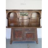 A Liberty Arts & Crafts oak dresser with a glazed single door and two shelves over the base with a