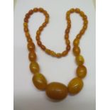 A string of amber type beads - largest 35mm x 26mm - total weight approx 83 grams - Length 75cm