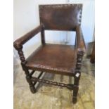 A 17th/18th century oak armchair with a worn leather seat back and arms - sound condition and a nice