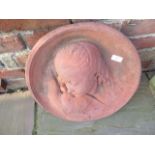 A weathered terracotta coloured cast stone roundel of a girl with dove - Diameter 44cm x Depth 11cm