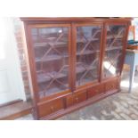 A mahogany three door astragal glazed bookcase with four base drawers - Height 141cm x 178cm x 32cm