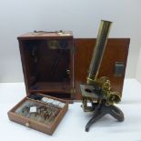 A brass microscope in a mahogany case with attachments and slides