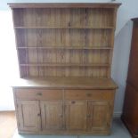 A Victorian stripped pine dresser with a graduating open rack top above a two drawer four door