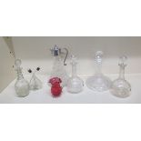 A moulded glass claret jug with a plated top, four glass decanters, oil bottle and a cranberry glass