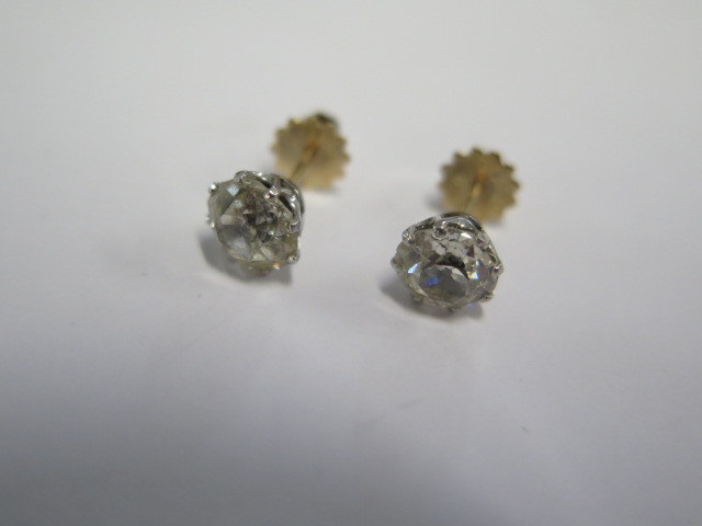 A pair of diamond stud earrings in gold and white metal settings with screw backs - each diamond