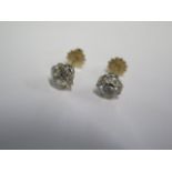 A pair of diamond stud earrings in gold and white metal settings with screw backs - each diamond
