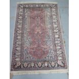 A silk pile rug with a pink field and stylized boarder - 155cm x 95cm - reasonably good condition,