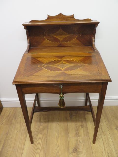 An inlaid mahogany writing table with a lift up sloping top enclosing a fitted interior and upstand