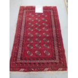 A hand knotted woollen Boukara rug with a red field - 193cm x 118cm - some wear to fringes otherwise