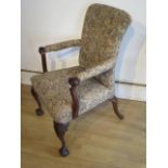 A carve mahogany upholstered open armchair with scroll arms on carved front legs and ball and claw