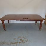 A 19th century mahogany wind out dining table with 2 leaves on turned reeded legs, 73cm tall,